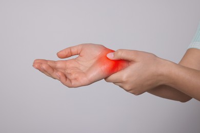 Image of Arthritis symptoms. Young woman suffering from pain in wrist on light grey background, closeup