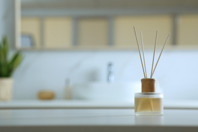 Photo of Aromatic reed air freshener on table indoors. Space for text