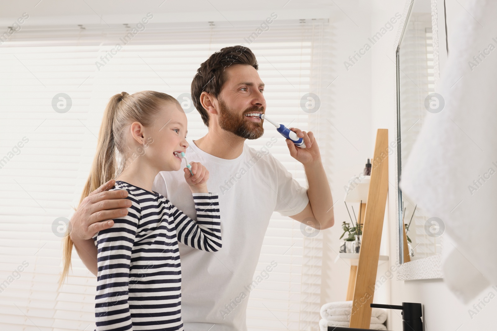 Photo of Father and his daughter brushing teeth together in bathroom