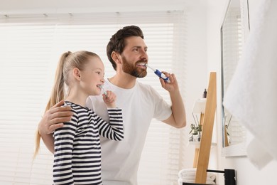 Father and his daughter brushing teeth together in bathroom