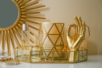 Composition with golden accessories and jewelry on dressing table near color wall