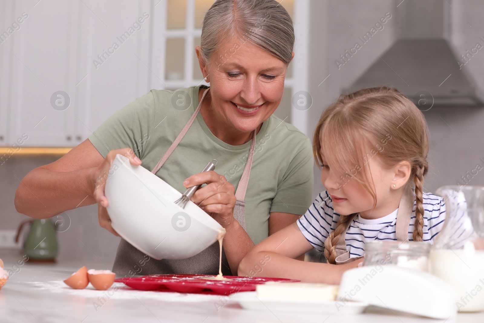 Photo of Happy grandmother with her granddaughter cooking together in kitchen