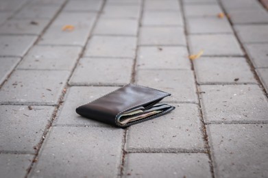 Photo of Black wallet on pavement outdoors. Lost and found
