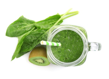 Green juice in mason jar and fresh ingredients on white background, top view