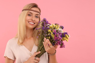 Photo of Portrait of smiling hippie woman with bouquet of flowers on pink background. Space for text