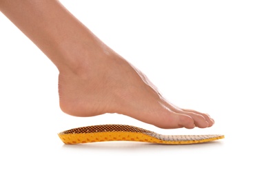 Woman fitting orthopedic insole on white background, closeup. Foot care