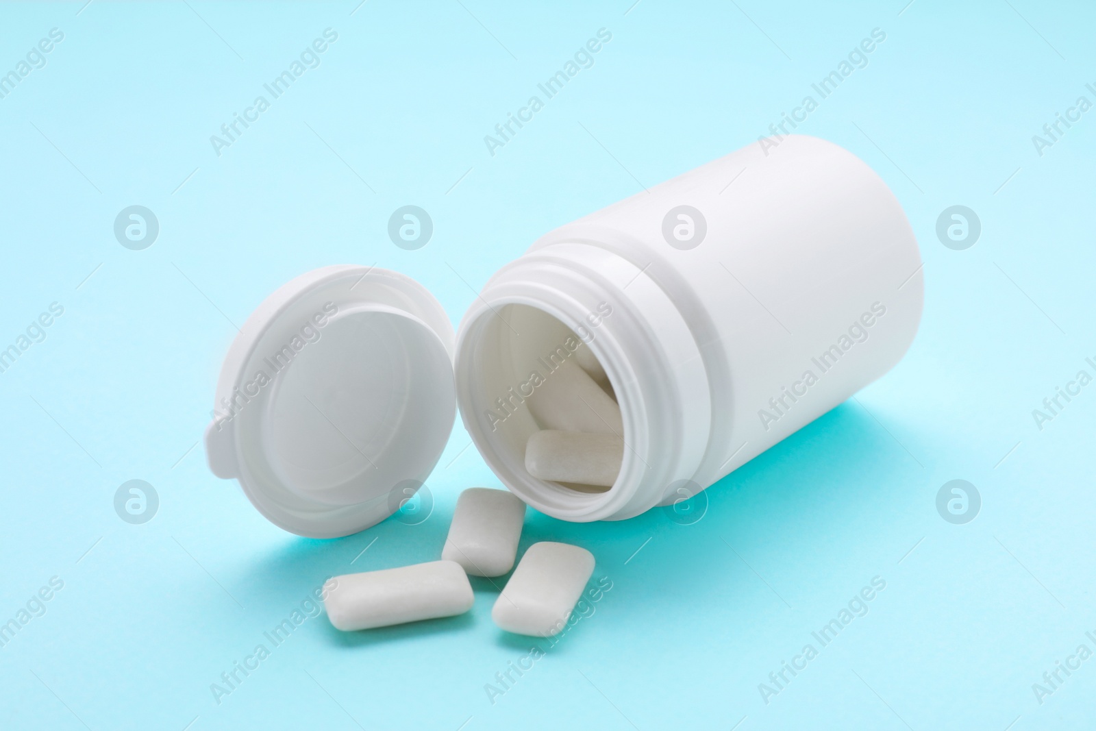 Photo of Jar with chewing gums on light blue background