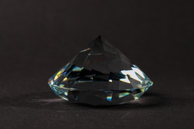 Beautiful dazzling diamond on dark background, closeup. Precious gemstone