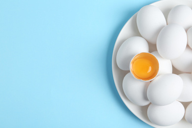 Photo of Fresh raw chicken eggs on light blue background, top view. Space for text