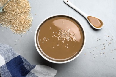 Photo of Tasty sesame paste and seeds on light grey table, flat lay