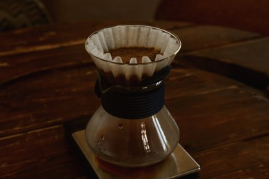Photo of Cup with wave dripper and coffee on wooden table in cafe