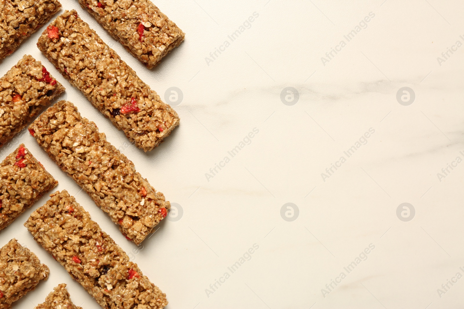 Photo of Tasty granola bars on white marble table, flat lay. Space for text