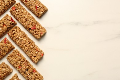 Photo of Tasty granola bars on white marble table, flat lay. Space for text