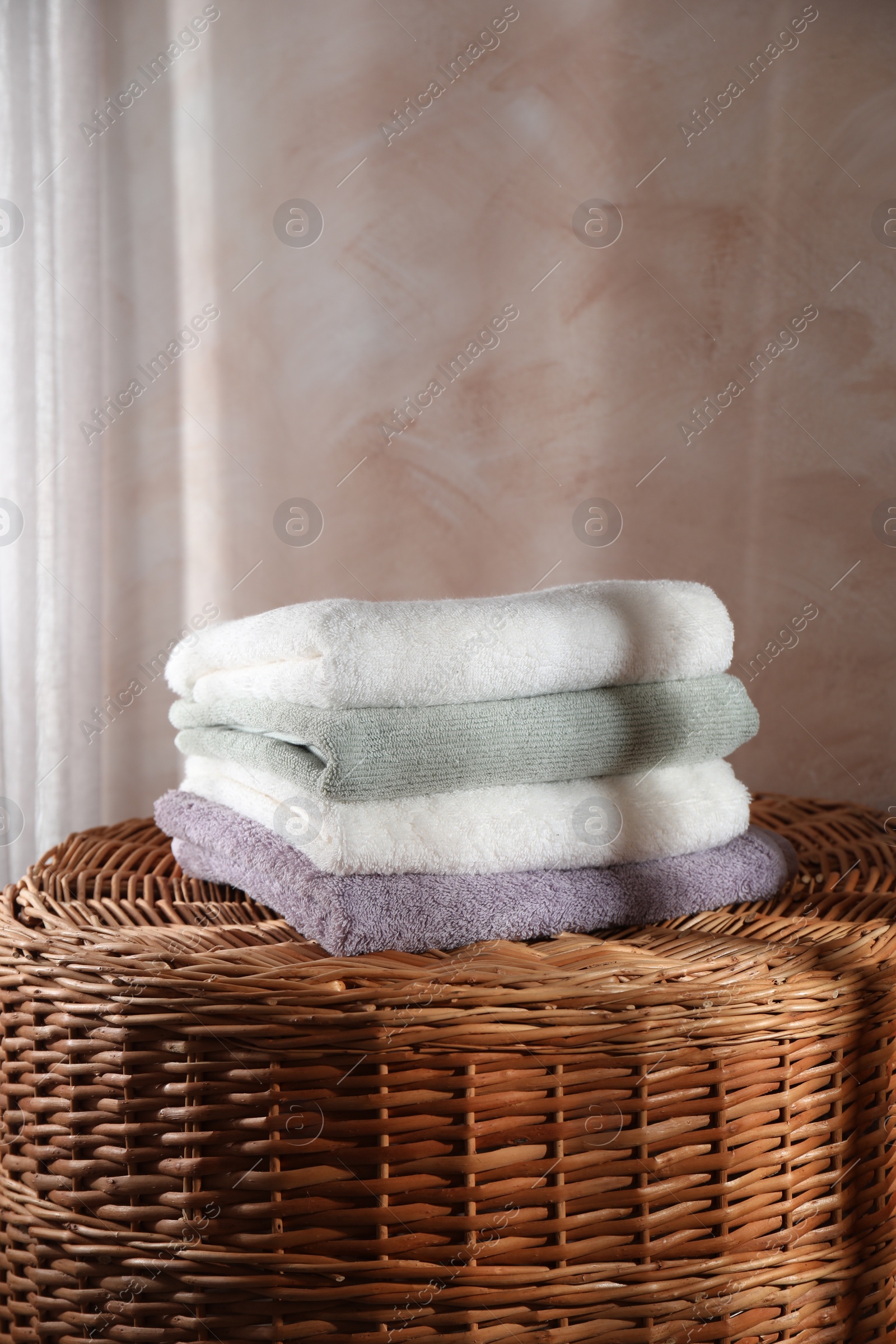 Photo of Stacked soft towels on rattan laundry basket indoors