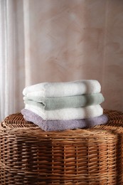 Stacked soft towels on rattan laundry basket indoors