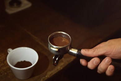 Photo of Barista preparing fresh aromatic coffee, closeup
