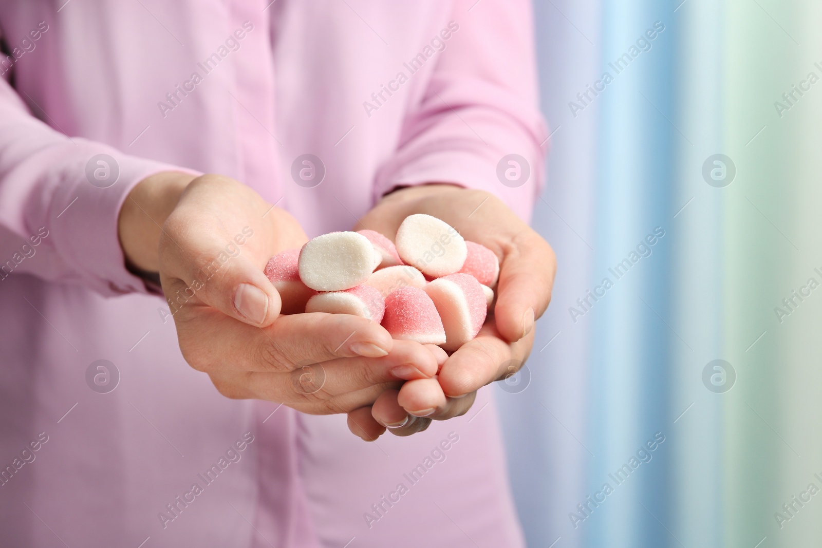 Photo of Young woman holding handful of tasty jelly candies on blurred background, closeup. Space for text