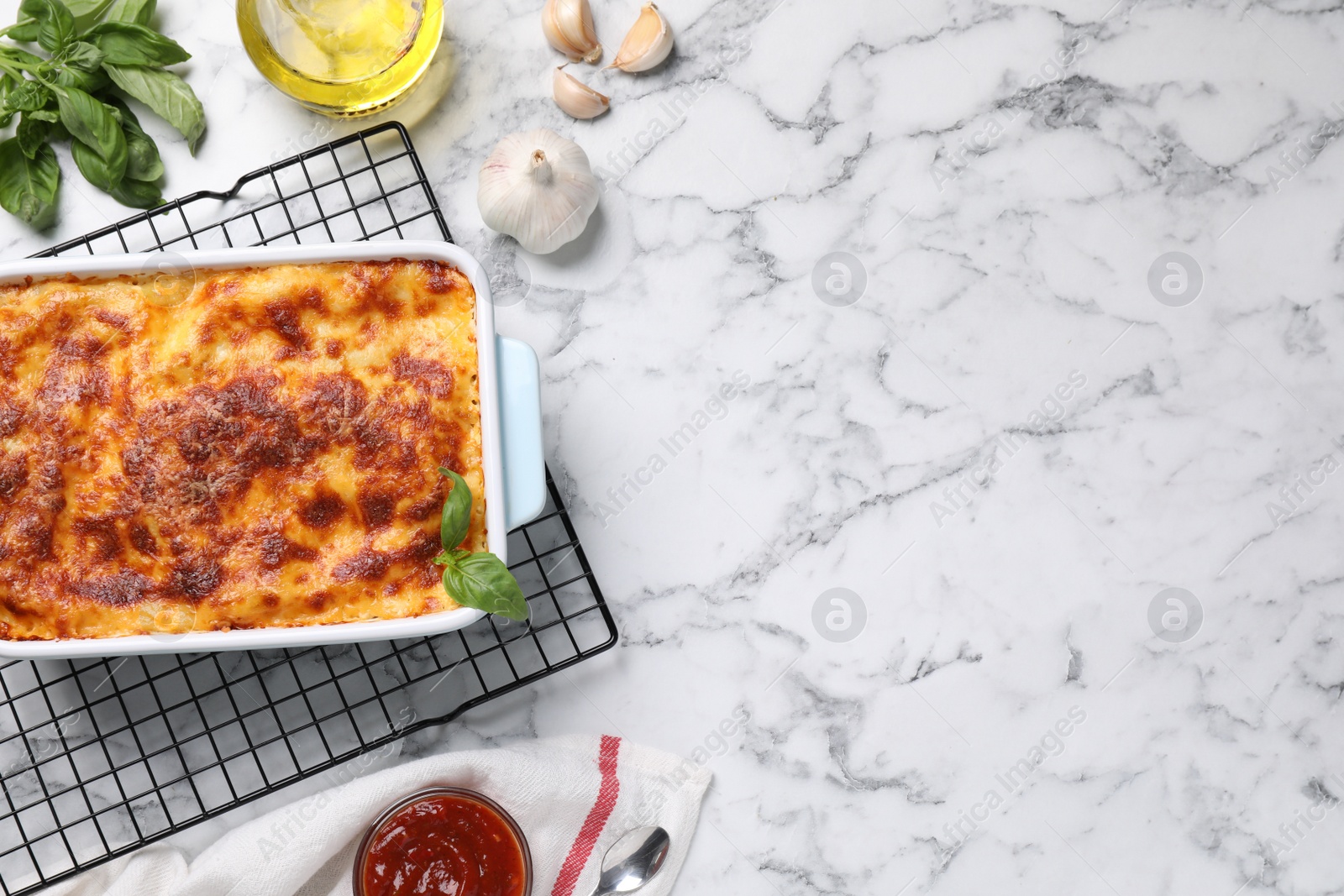 Photo of Tasty cooked lasagna in baking dish on white marble table, flat lay. Space for text