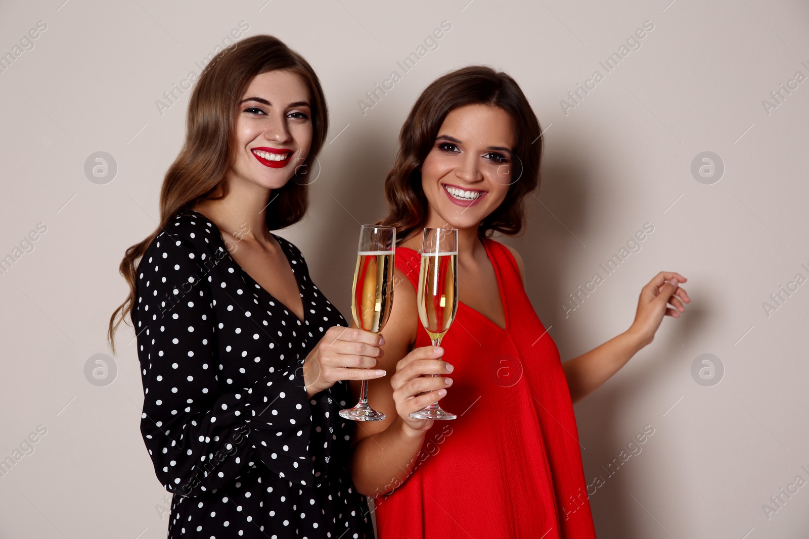 Photo of Happy women with champagne on beige background. Christmas party