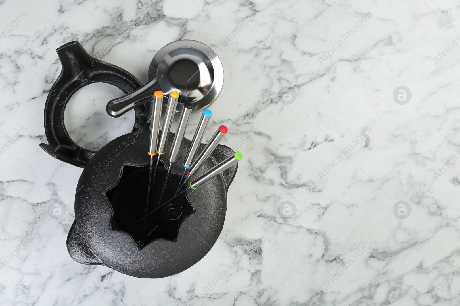 Photo of Fondue set on white marble table, flat lay. Space for text