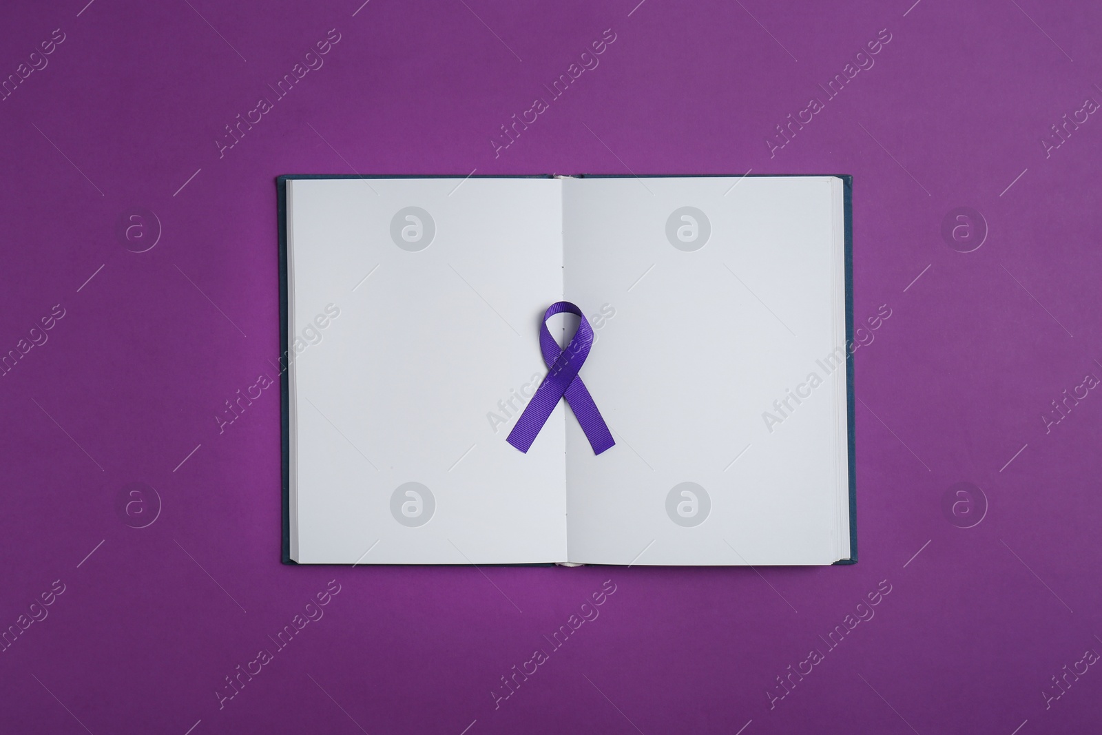 Photo of Purple awareness ribbon and open notebook on color background, top view