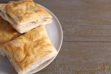 Photo of Delicious fresh puff pastries on wooden table, closeup. Space for text