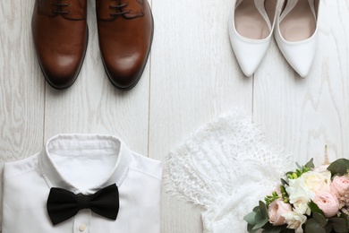 Photo of Flat lay composition with wedding shoes for bride and groom on white wooden floor