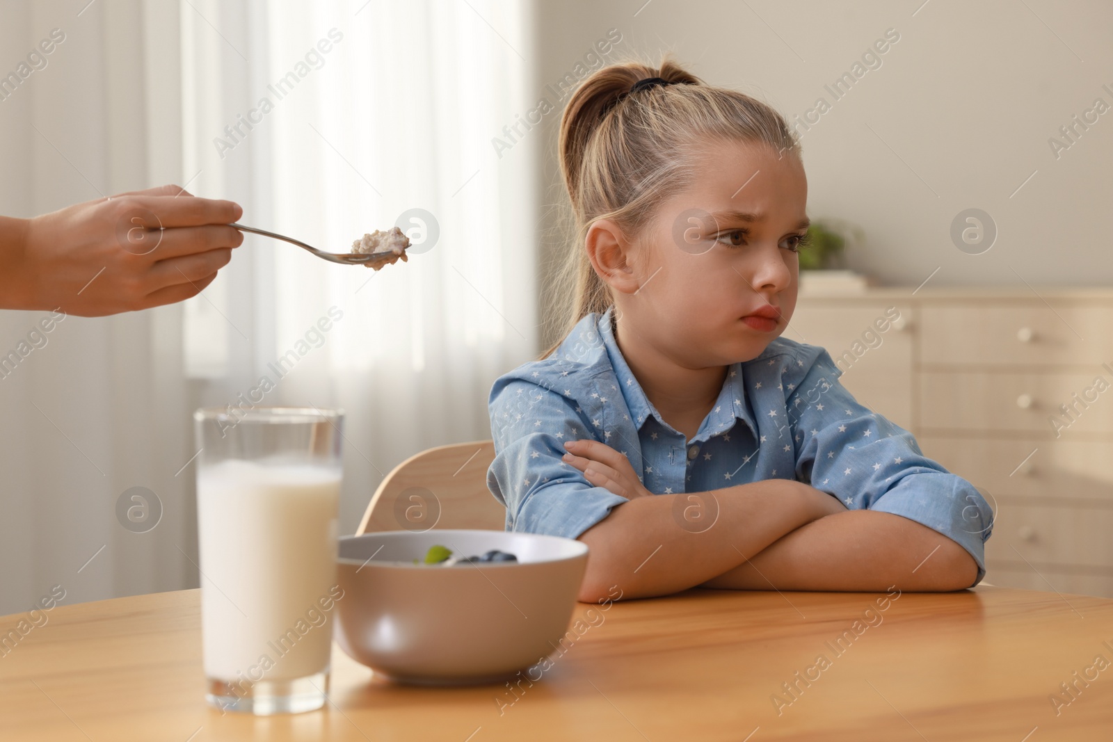 Photo of Cute little girl refusing to eat her breakfast at home