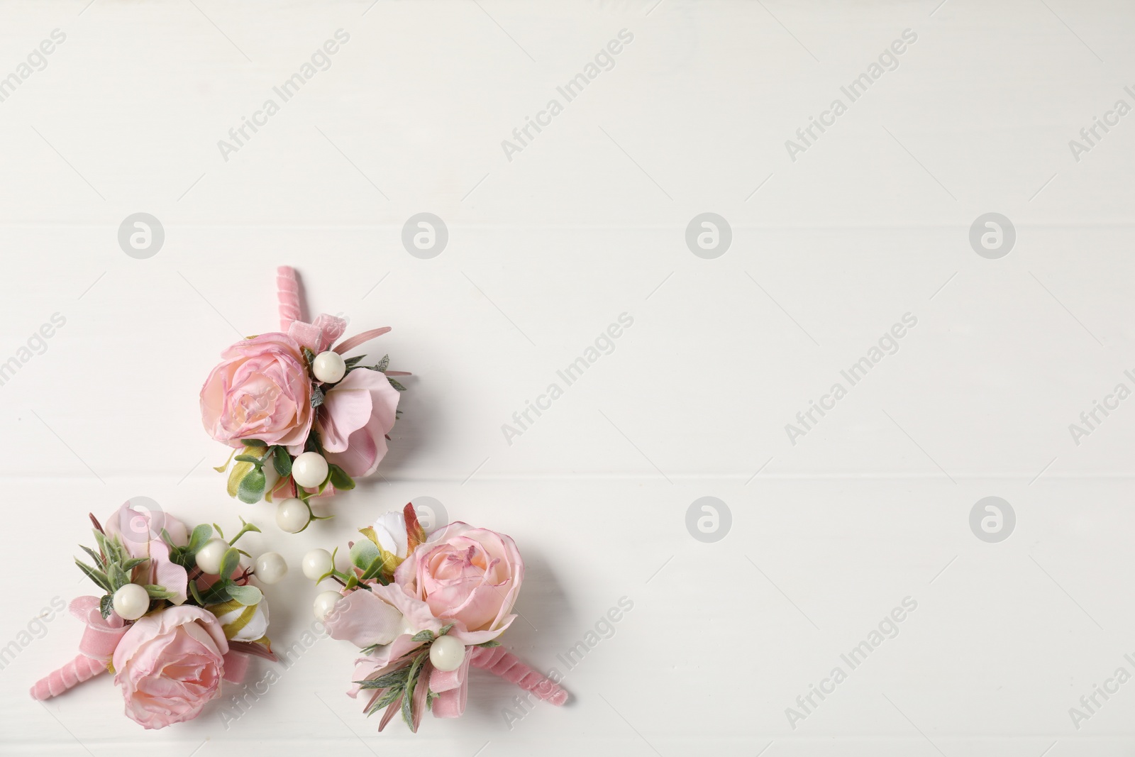 Photo of Beautiful boutonnieres on white background, flat lay. Space for text