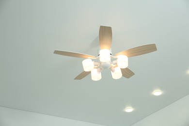 Photo of Ceiling fan with lamps indoors, low angle view