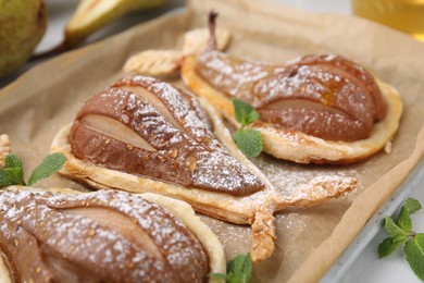 Photo of Delicious pears baked in puff pastry with powdered sugar and mint on table, closeup