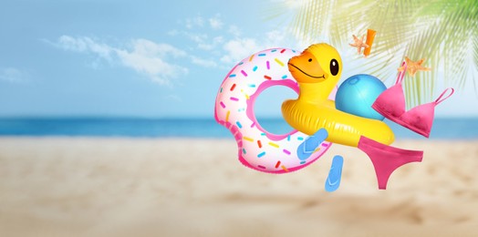 Image of Sunscreen and beach accessories flying over sandy beach. Banner design with space for text