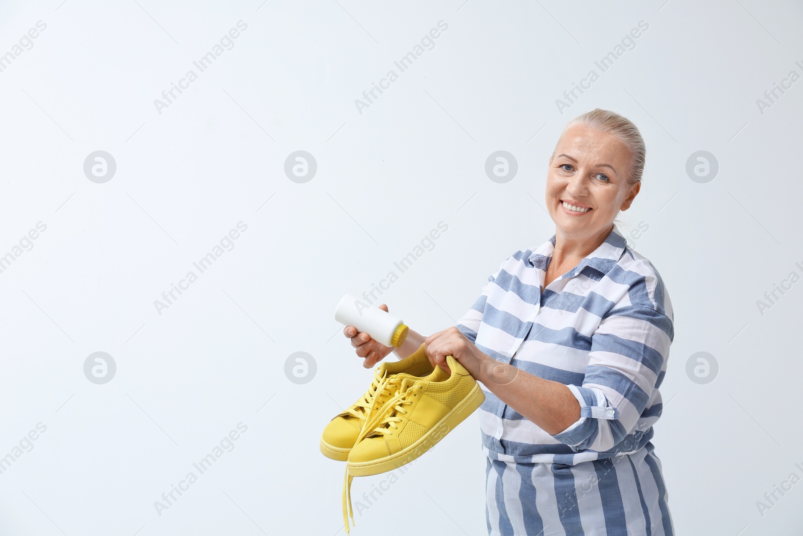 Photo of Woman putting powder shoe freshener in footwear on white background. Space for text