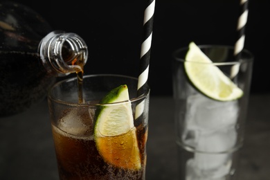 Photo of Pouring refreshing soda drink into glass on black background, closeup. Space for text