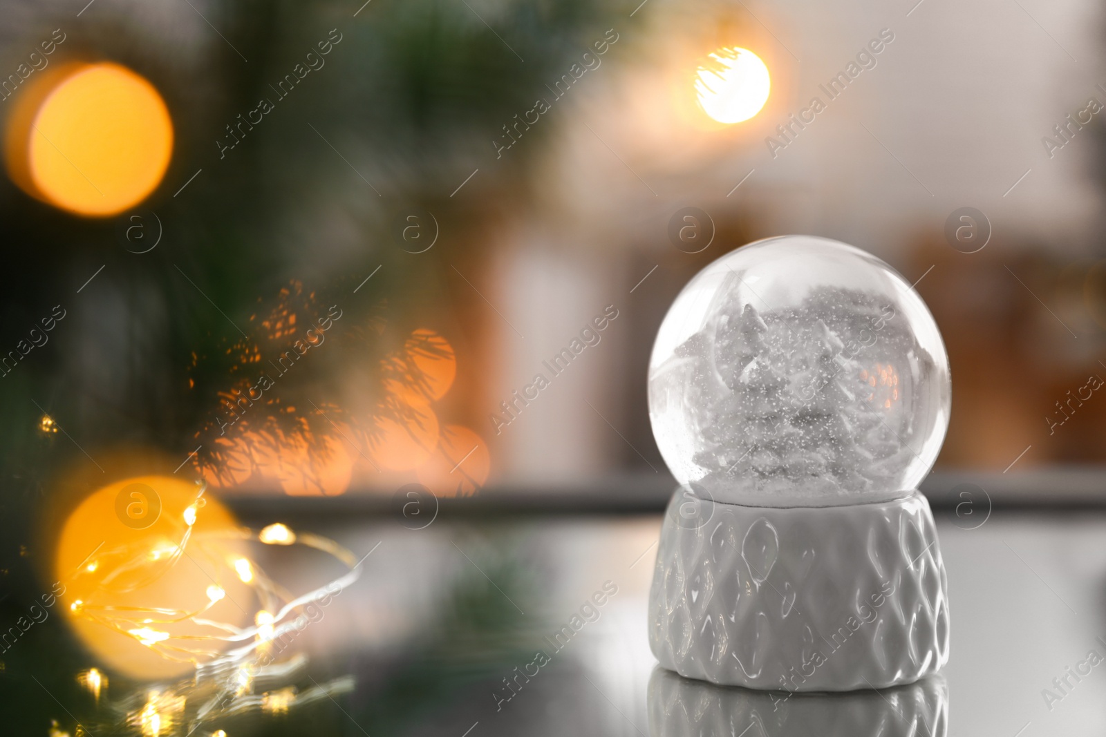 Photo of Decorative Christmas snow globe on mirror surface