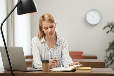 Photo of Young woman reading book at table in library