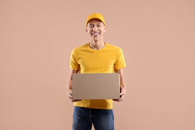 Photo of Happy courier with parcel on beige background. Space for text