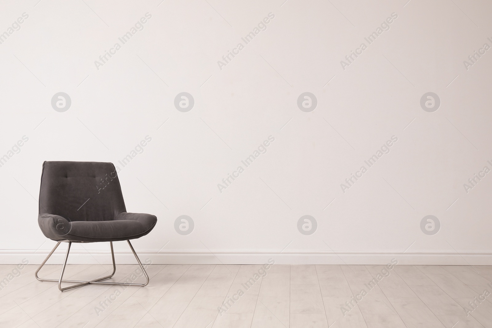 Photo of Stylish comfortable chair near white wall, space for text. Interior design