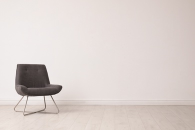 Photo of Stylish comfortable chair near white wall, space for text. Interior design