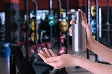 Image of Woman applying antiseptic gel at gym, closeup. Preventive measures during epidemic period 