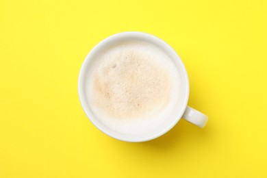 Photo of Aromatic coffee in cup on yellow background, top view