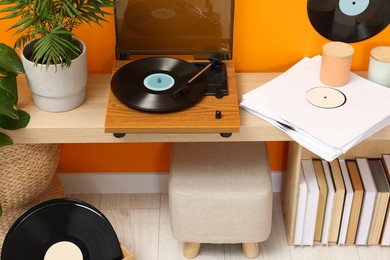 Stylish turntable with vinyl record on console table in cozy room