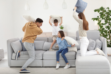 Photo of Happy family having pillow fight in living room