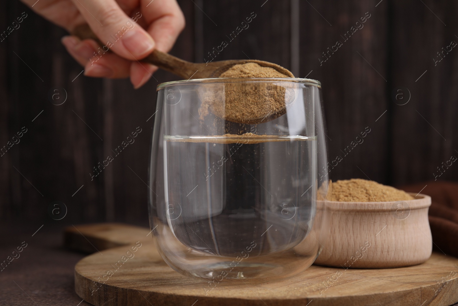 Photo of Dietary fiber. Woman adding psyllium husk powder into water at table, closeup