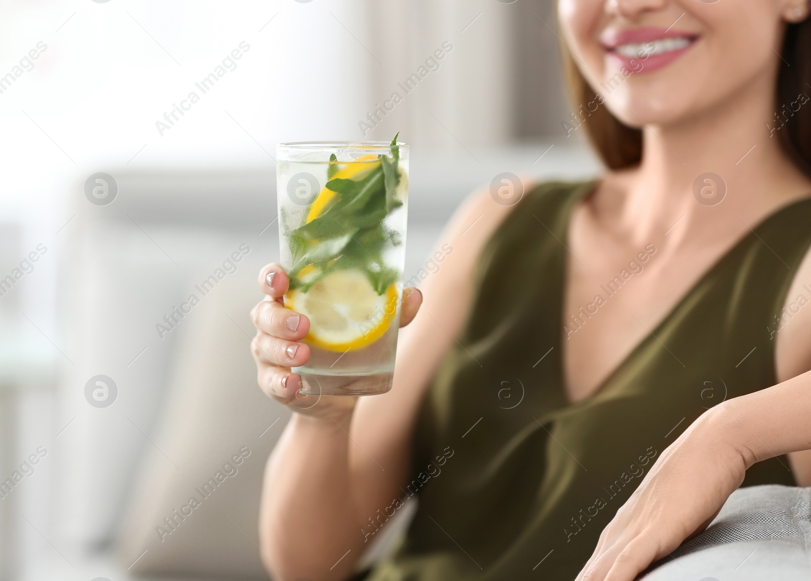 Photo of Young woman with lemonade at home, closeup. Refreshing drink