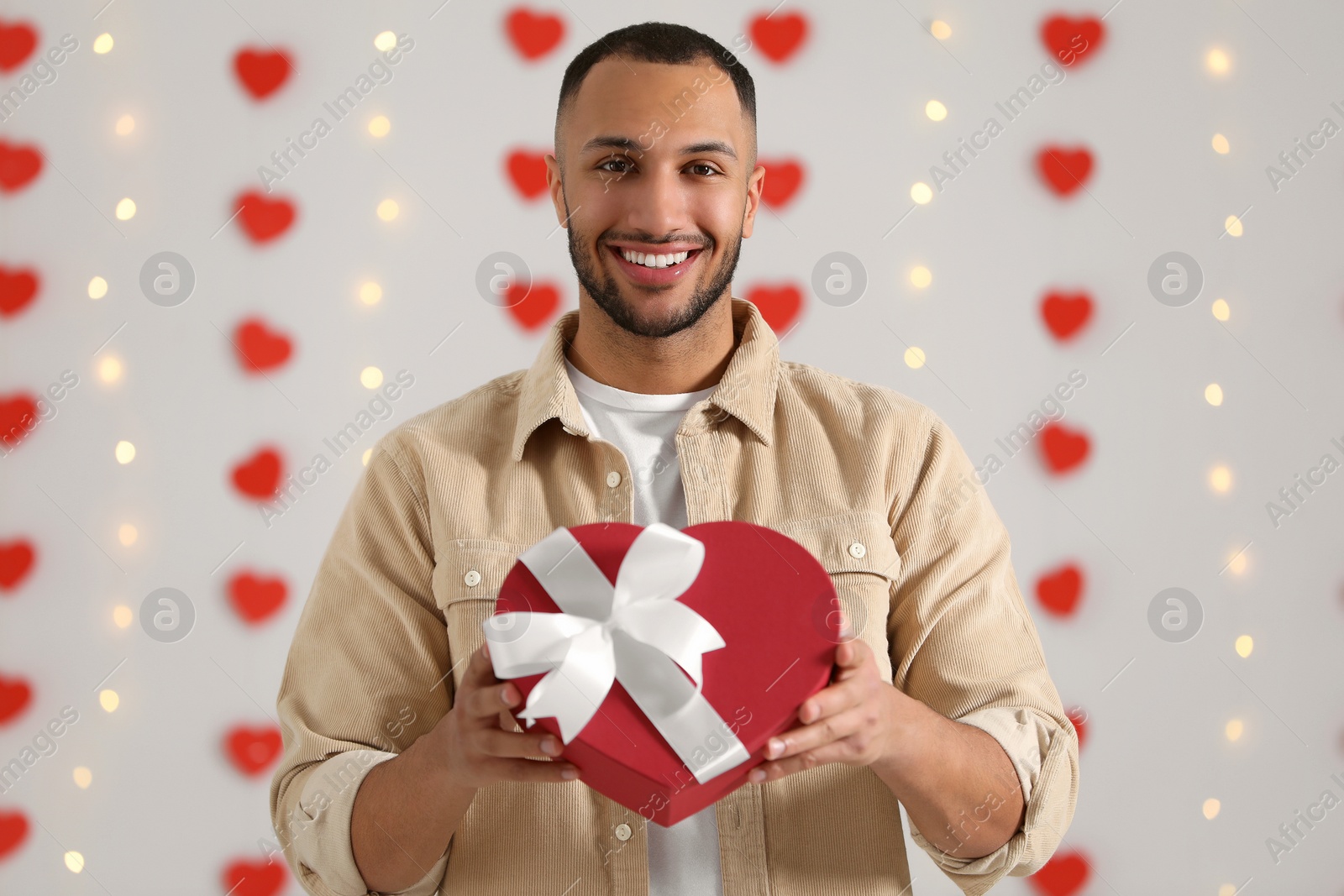 Photo of Handsome man with gift box indoors, view from camera. Valentine's day celebration in long distance relationship