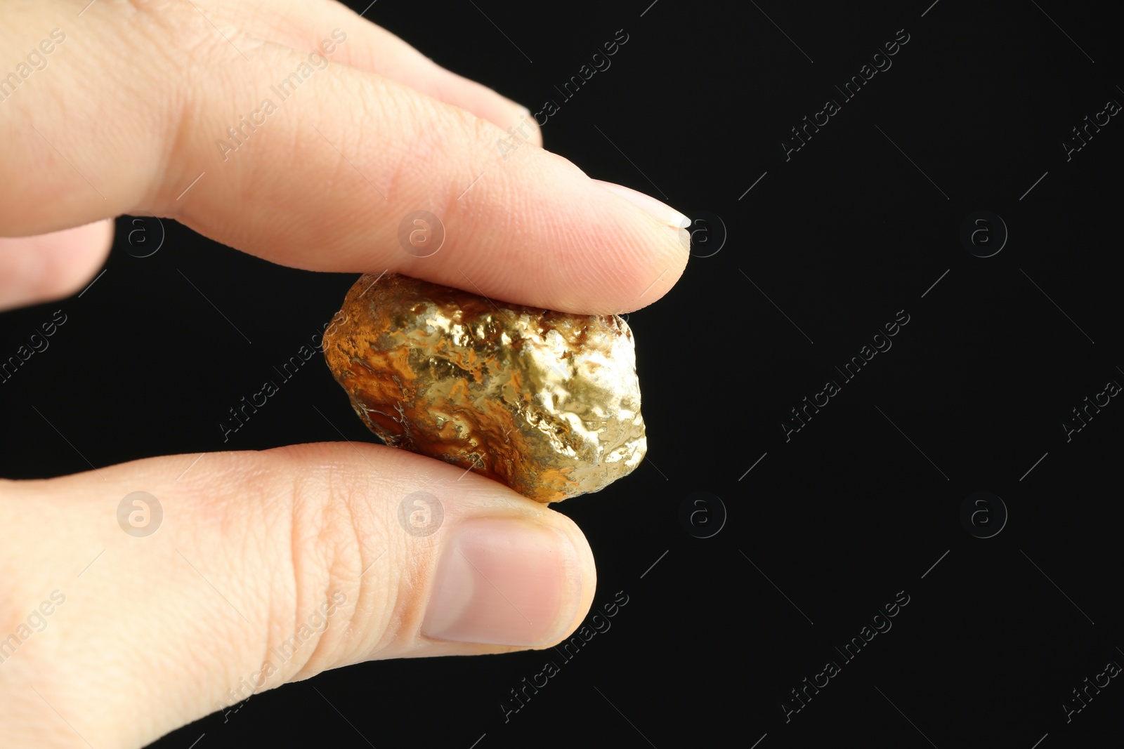 Photo of Woman holding gold nugget against black background, closeup. Space for text