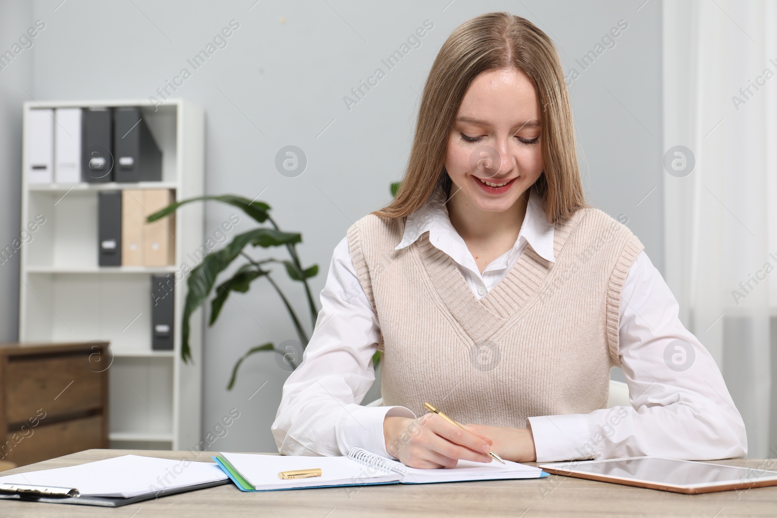 Photo of Woman taking notes at wooden table in office