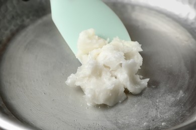Photo of Frying pan with coconut oil and spatula, closeup