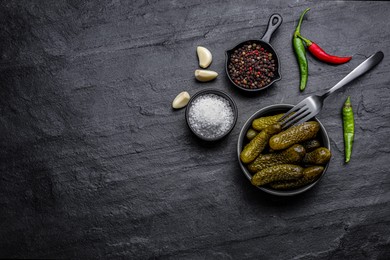 Photo of Bowl of pickled cucumbers and ingredients on black table, flat lay. Space for text